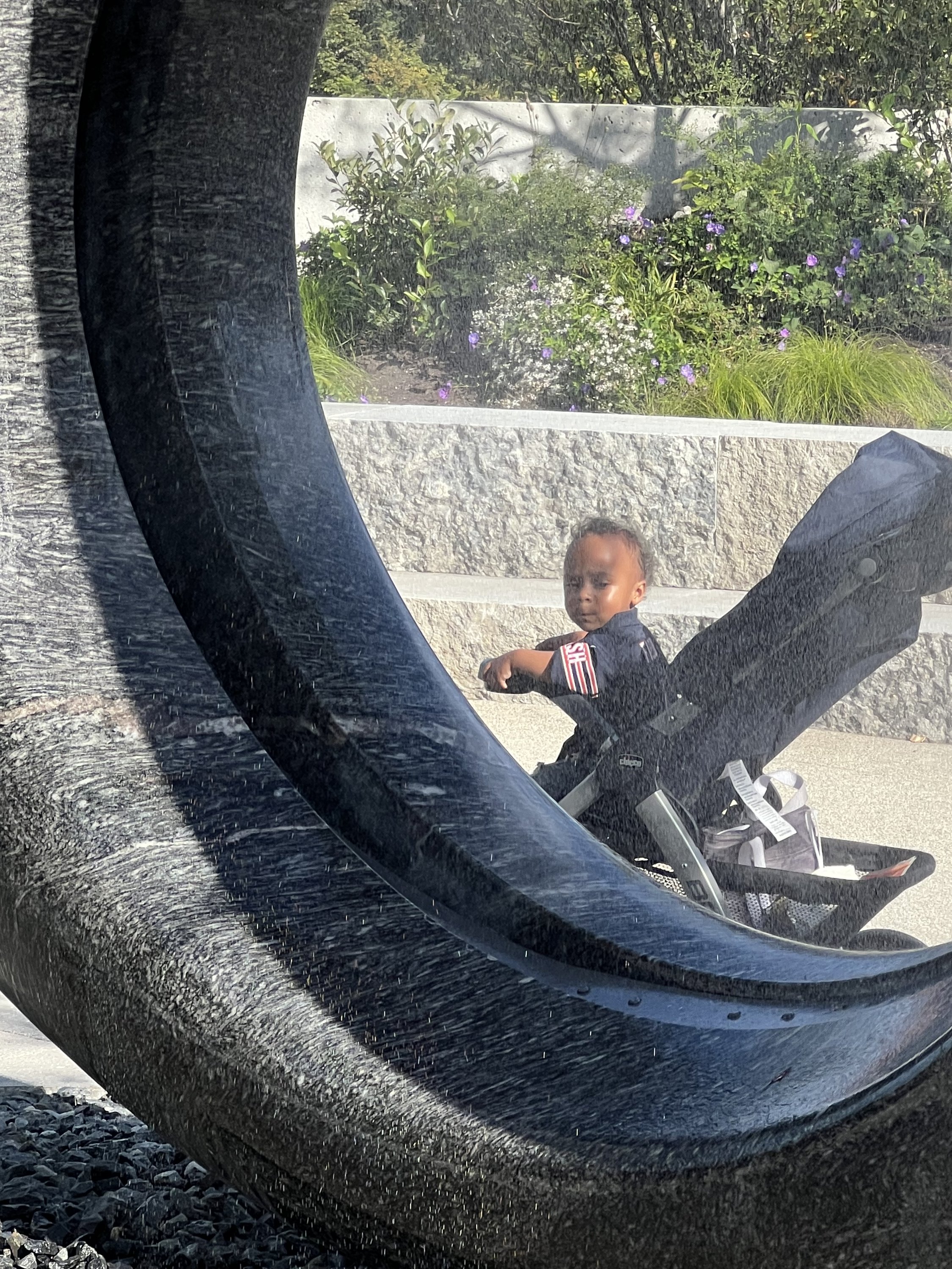 Kobra, a young visitor, looking through the water mist, “Seeing Through the Universe,” Maya Lin’s sculptural water installation, two rounded granite forms, Outdoor Grounds/ Ann Dunham Water Terrace/ Obama Presidential Center. September 2026. Photo: S. Zetouni